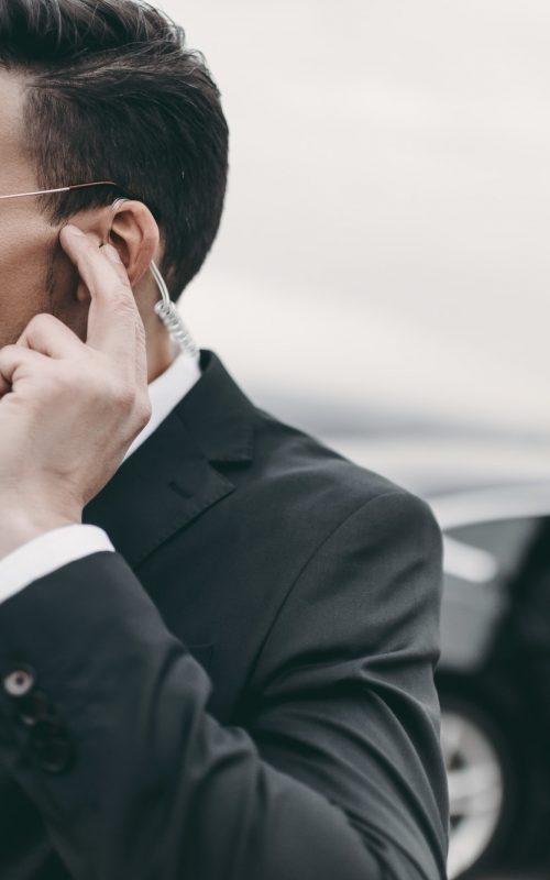 handsome bodyguard of businessman listening message with security earpiece